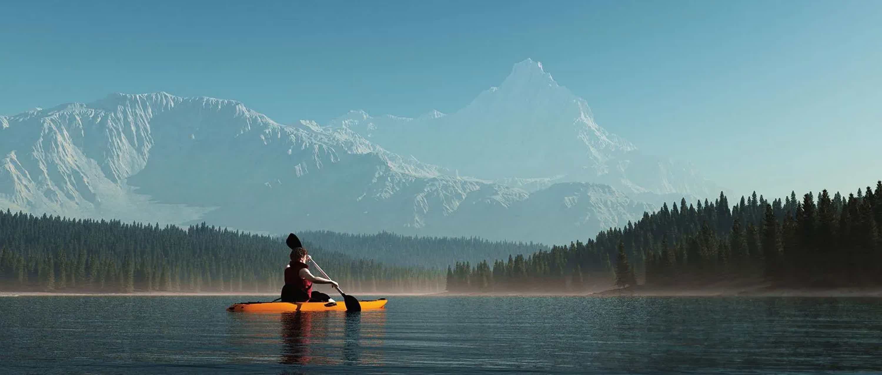Kayaker paddling a calm mountain lake with snow-capped peaks beyond the treeline